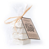 4 small square bars of lavender goat milk soap packaged in a clear bag tied with raffia